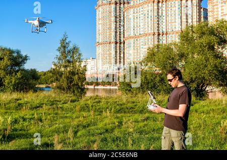 MOSKAU - 9. AUGUST 2016: Mann, der einen Drohnen-Quad-Copter mit integrierter Digitalkamera im Stadtpark betreibt. Stockfoto