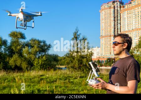 Mann, der einen Drohnen-Quad-Copter mit integrierter Digitalkamera im Stadtpark betreibt Stockfoto