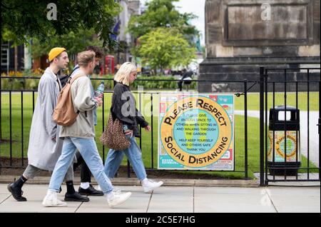 Die Mitglieder der Öffentlichkeit gehen an einem Schild vorbei, auf dem steht: "Bitte respektieren Sie soziale Distanzierung" am St Andrews Square in Edinburgh. Stockfoto