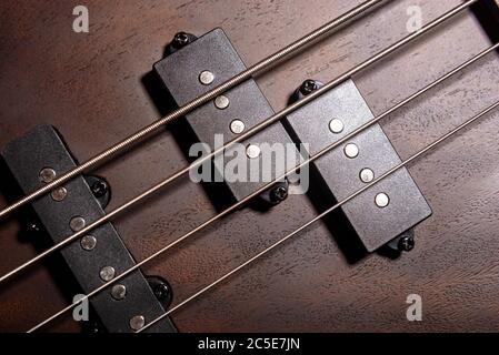 Bass E-Gitarre mit vier Saiten Nahaufnahme. Detail des populären Rock Musikinstruments. Nahansicht von Holzbass mit Struktur. Makrofoto der Pickups Stockfoto