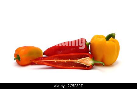 Zusammensetzung von mehreren Paprika und ihre Hälften in verschiedenen Farben auf einem hellen Hintergrund. Naturprodukt. Natürliche Farbe. Nahaufnahme. Stockfoto