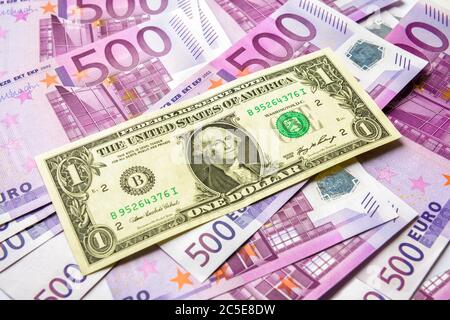 1 Dollar-Schein im Vergleich zu vielen 500 Euro-Geldscheinen. Währung der Europäischen Union unter einem US-Dollar. Draufsicht auf den Stapel von gemischtem Geld Bargeld. Konz Stockfoto
