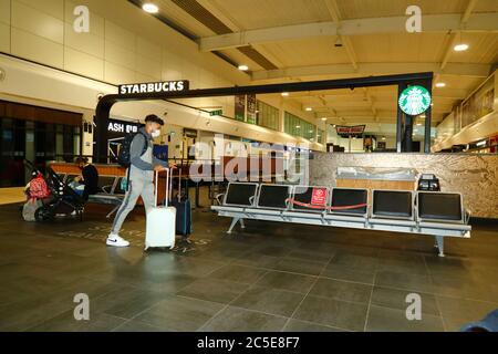 2nd. Juli 2020, Flughafen Luton, Großbritannien: Ein Passagier mit Gesichtsmaske geht an einem geschlossenen Starbucks-Café in den Abflughallen des Flughafens Luton vorbei. Die Zahl der Flüge aus dem Vereinigten Königreich in einige europäische Länder nimmt zu, und die Regierungen werden voraussichtlich bald Flugbrücken zwischen den Ländern ankündigen, um Reisen und Tourismus zu erleichtern. Die wirtschaftlichen Auswirkungen des Virus auf den Einzelhandel und andere Sektoren werden schwerwiegend sein, und viele Unternehmen werden noch geschlossen sein Stockfoto