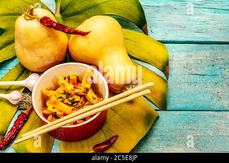 Hobak Kürbis Kimchi. Koreanische traditionelle herzhafte Speisen. Würzige marinierte Stücke, duftende Gewürze, frisches Gemüse. Trendy türkis Holzbretter hintergr Stockfoto