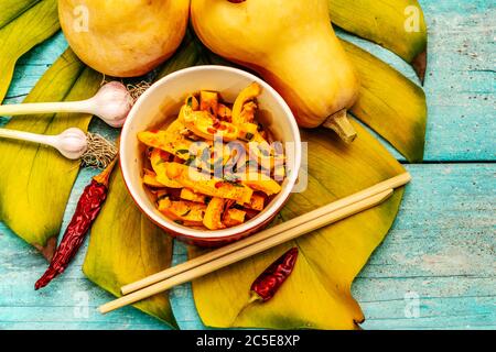 Hobak Kürbis Kimchi. Koreanische traditionelle herzhafte Speisen. Würzige marinierte Stücke, duftende Gewürze, frisches Gemüse. Trendy türkis Holzbretter hintergr Stockfoto