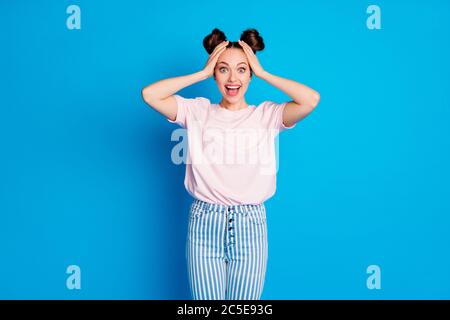 Foto von ziemlich schockiert Dame zwei lustige Brötchen fröhlich hören gute Nachrichten offenen Mund Arme auf dem Kopf tragen lässig weiß rosa T-Shirt gestreiften Jeans Hose Stockfoto