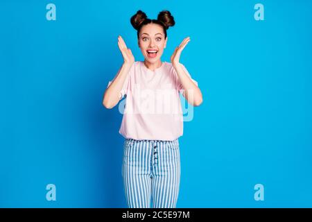 Foto von attraktiven schockiert Dame zwei lustige Brötchen fröhlich Stimmung hören gute Nachrichten offenen Mund Arme in der Nähe Wangen tragen beiläufige weiß rosa T-Shirt gestreift Stockfoto