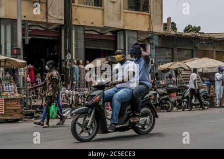 Dakar, Senegal. Juli 2020. Zwei Männer mit Gesichtsmasken fahren am 1. Juli 2020 in Dakar, Senegal, auf einem Motorrad. Vier Monate nach Ausbruch der COVID-19-Pandemie am 2. März in Senegal haben die bestätigten Fälle am Donnerstag die Marke von 7,000 überschritten. Kredit: Eddy Peters/Xinhua/Alamy Live Nachrichten Stockfoto