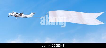 Flugzeug fliegt in den Himmel mit einem weißen Banner für Werbung. Stockfoto