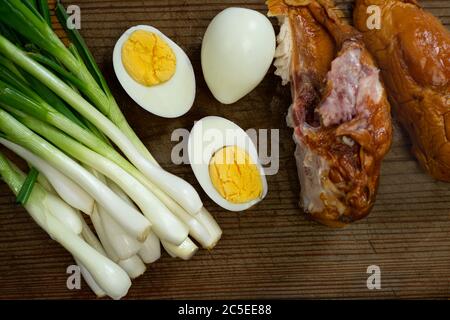 Gekochte Eier, frischer Schnittlauch und geräuchertes Huhn auf einem Brett Stockfoto