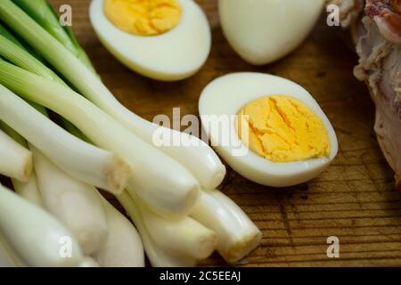 Gekochte Eier, frischer Schnittlauch und geräuchertes Huhn auf einem Brett Stockfoto