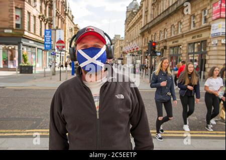 Glasgow, Schottland, Großbritannien. Juli 2020. Im Bild: Ein Mann, der eine Gesichtsmaske mit der St Andrews Scotland Flag trägt. Szenen aus Glasgows Stil Meile, Buchanan Street Einkaufsviertel, wo mehr Menschen mit Gesichtsmasken oder hausgemachte Gesichtsbezüge gesehen werden. Nicola Sturgeon hat heute angekündigt, dass das Tragen einer Gesichtsbedeckung ab dem 10. Juli nächste Woche in den Geschäften obligatorisch sein wird. Gesichtsbedeckungen sind bereits obligatorisch, wenn man öffentliche Verkehrsmittel nimmt, um die Ausbreitung des Coronavirus zu verlangsamen. Quelle: Colin Fisher/Alamy Live News Stockfoto