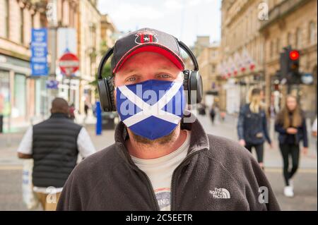 Glasgow, Schottland, Großbritannien. Juli 2020. Im Bild: Ein Mann, der eine Gesichtsmaske mit der St Andrews Scotland Flag trägt. Szenen aus Glasgows Stil Meile, Buchanan Street Einkaufsviertel, wo mehr Menschen mit Gesichtsmasken oder hausgemachte Gesichtsbezüge gesehen werden. Nicola Sturgeon hat heute angekündigt, dass das Tragen einer Gesichtsbedeckung ab dem 10. Juli nächste Woche in den Geschäften obligatorisch sein wird. Gesichtsbedeckungen sind bereits obligatorisch, wenn man öffentliche Verkehrsmittel nimmt, um die Ausbreitung des Coronavirus zu verlangsamen. Quelle: Colin Fisher/Alamy Live News Stockfoto