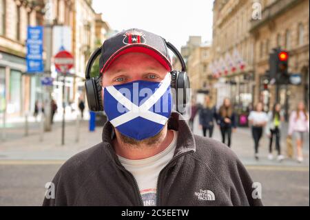 Glasgow, Schottland, Großbritannien. Juli 2020. Im Bild: Ein Mann, der eine Gesichtsmaske mit der St Andrews Scotland Flag trägt. Szenen aus Glasgows Stil Meile, Buchanan Street Einkaufsviertel, wo mehr Menschen mit Gesichtsmasken oder hausgemachte Gesichtsbezüge gesehen werden. Nicola Sturgeon hat heute angekündigt, dass das Tragen einer Gesichtsbedeckung ab dem 10. Juli nächste Woche in den Geschäften obligatorisch sein wird. Gesichtsbedeckungen sind bereits obligatorisch, wenn man öffentliche Verkehrsmittel nimmt, um die Ausbreitung des Coronavirus zu verlangsamen. Quelle: Colin Fisher/Alamy Live News Stockfoto