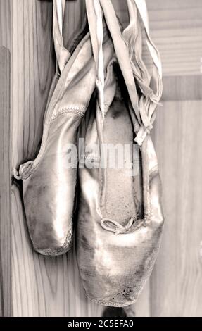 Ein Paar abgenutzte Ballettschuhe, die an den Bändern hängen. Stockfoto