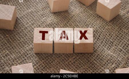 Steuerwort aus Buchstaben auf Holzblöcken, die auf einer Sackleinen-Leinwand stehen. Geschäftssteuern und Gebühren Konzept Stockfoto