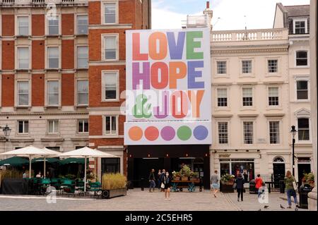 London, UK, 2. Juli 2020 Poster 'Liebe, Hoffnung und Freude in Covent Garden. Von Anthony Burrill, sein bisher größter, feiert die Wiedereröffnung des sind nach der Lockerung der Einschränkungen für die Pandemie des Coronavirus. Zu sehen bis Oktober 2020. West End bereitet sich auf Super Saturday vor, da die Pubs geöffnet sind. Viele Unternehmen zeigen keine Anzeichen von Öffnung, da das Hotel und die Theater geschlossen bleiben und es erleichtert wird. Kredit: JOHNNY ARMSTEAD/Alamy Live Nachrichten Stockfoto