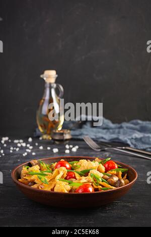 Feigwaren mit Gemüse, Blumenkohl und Pilzen unter Rühren braten Stockfoto