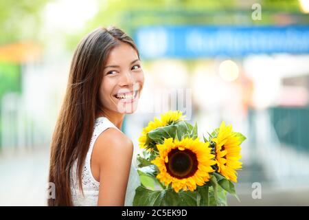 Frau hält Sonnenblumenblume lächelnd glücklich Stockfoto