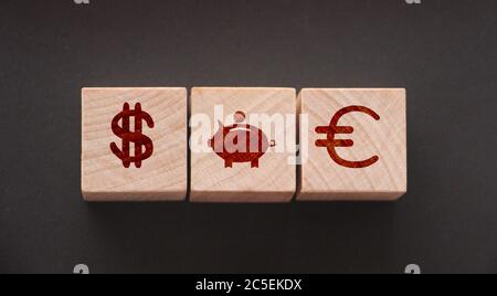 Holzwürfel mit US-Dollar, Sparschwein und Euro-Zeichen. Investitions- und Sparkonzept Stockfoto