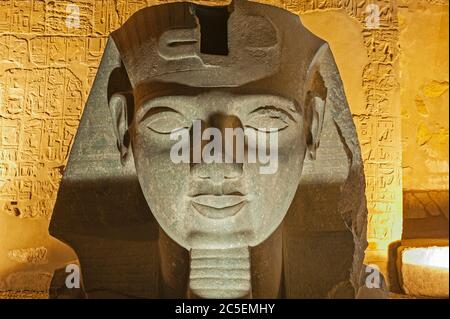 Großer Kopf der Statue von Ramses II am Eingang zum alten ägyptischen Luxor Tempel beleuchtet während der Nacht Stockfoto