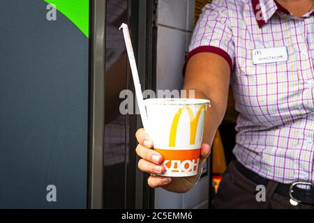 Sankt-Petersburg/Russland - Juli 11 2019: McDonald’s Arbeiter hält Tasse Fast-Food-Drink. Hand mit einer Cola-Tasse durch das Fenster von mcdonalds Auto dri Stockfoto