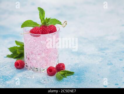 Erfrischender Cocktail aus rosa Limonade in Kristallglas mit Himbeeren, Eis und Minze auf hellblauem Hintergrund. Leerzeichen für Text Stockfoto