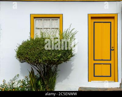 Fassade eines alten Hauses mit gelben Türen und kleinem Garten in der historischen Stadt Diamantina, Minas Gerais Staat, Brasilien Stockfoto