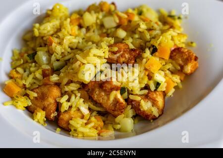 Paella mit Fleisch, Pfeffer, Gemüse und Gewürzen auf dem Teller Stockfoto