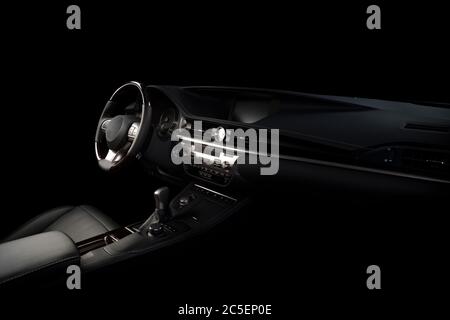 Moderne Luxus Prestige Auto Innenraum, Armaturenbrett, Lenkrad. Innenausstattung aus schwarzem Leder. Isoliert über schwarzem Hintergrund Stockfoto