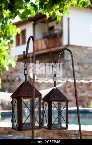 Alte rostige Laternen Lampen auf Holz Outdoor-Tisch als Gartendekoration in traditionellen National Revival Architektur Stil Haus Hinterhof in Bulgarien Stockfoto