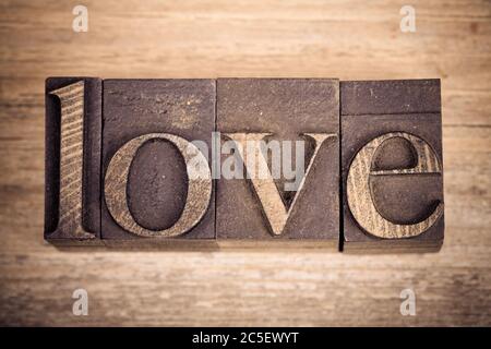 Das Wort LOVE Wriiten mit Vintage-Druck schaut auf alten Holzhintergrund Stockfoto