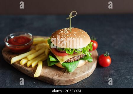 Fast Food Burger-Menü, pommes Frites und Ketchup-Sauce auf dunklem Hintergrund. Stockfoto