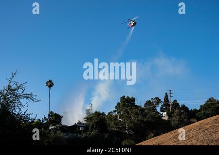 Notfall-Feuerwehr Hubschrauber Tropfen Wasser auf eine Bürste Feuer speichern Häuser in einem Kalifornien wilden Feuer. Stockfoto