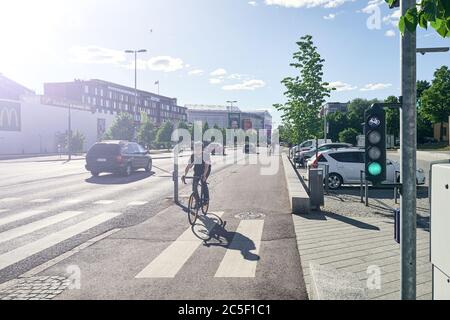 Helsinki / Finnland - 12. Juni 2018: Der Mann fährt auf dem Radweg mit dem Fahrrad. Grüne Ampel für Fahrrad ist an. Stockfoto