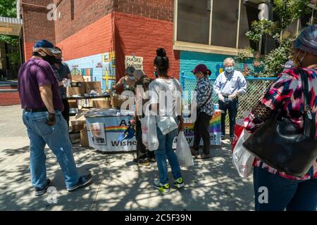 Die New Yorker holen am Donnerstag, den 25. Juni 2020, an einem Tisch des NYS-Vereinen Richard Gottfried im New Yorker Stadtteil Chelsea kostenlose Masken und Handdesinfektionsmittel ab. (© Richard B. Levine) Stockfoto