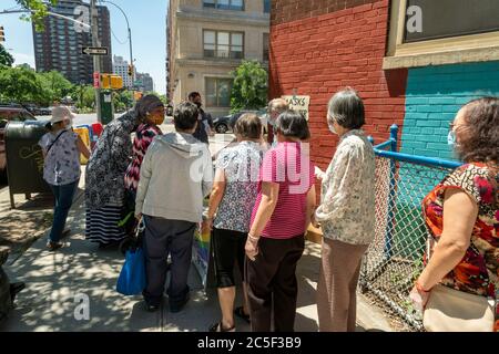 Die New Yorker holen am Donnerstag, den 25. Juni 2020, an einem Tisch des NYS-Vereinen Richard Gottfried im New Yorker Stadtteil Chelsea kostenlose Masken und Handdesinfektionsmittel ab. (© Richard B. Levine) Stockfoto