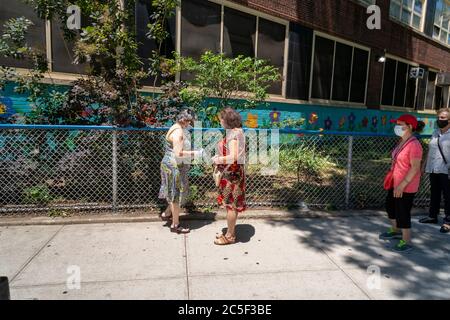 Die New Yorker holen am Donnerstag, den 25. Juni 2020, an einem Tisch des NYS-Vereinen Richard Gottfried im New Yorker Stadtteil Chelsea kostenlose Masken und Handdesinfektionsmittel ab. (© Richard B. Levine) Stockfoto