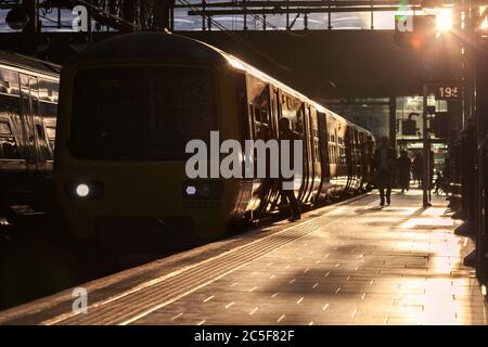 Silhouetten von Passagieren, die an einem Sommerabend in einen elektrischen Zug der Northern-Klasse 323 am Bahnhof Manchester Piccadilly einsteigen Stockfoto