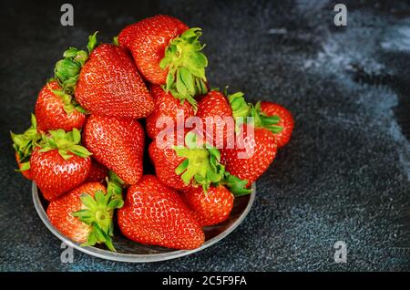 Gesundes Lebensmittelkonzept. Frische Erdbeeren auf dunklem Grund. Stockfoto