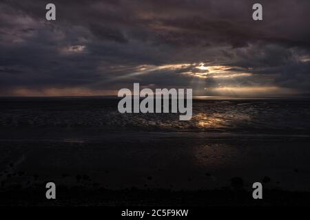 Vom schwarzen Himmel fallen Lichtwellen über den Strand der Morecambe Bucht bei Bolton Le Sands Stockfoto