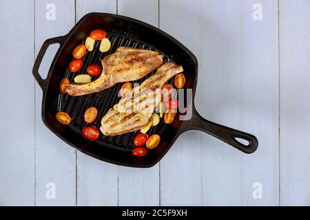 Gekochtes Steak in eiserner Pfanne auf weißem Holzhintergrund. Stockfoto