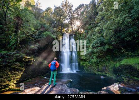 Wanderer im McLean Wasserfall, Sun Star, Catlins, Otago, South Island, Neuseeland Stockfoto