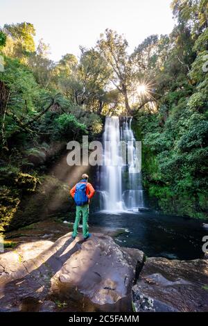 Wanderer im McLean Wasserfall, Sun Star, Catlins, Otago, South Island, Neuseeland Stockfoto