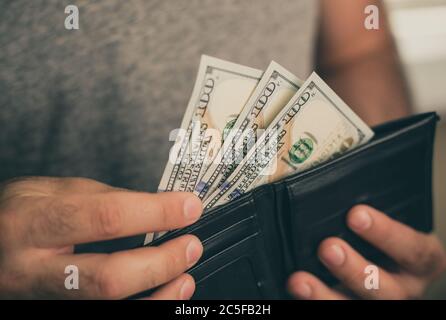 Mann schaut in die Brieftasche. Bargeld. Wohlhabender Mann, der sein Geld zählt. Nahaufnahme. Stockfoto