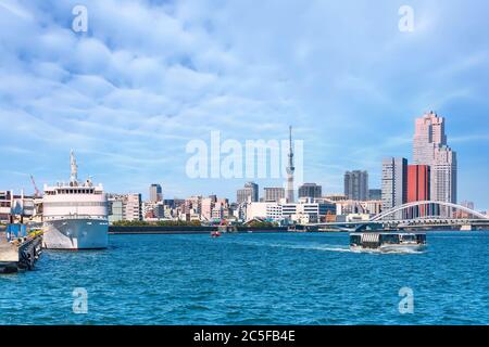 tokio, japan - märz 15 2020: Bogenbrücke von Tsukiji Ohashi am Sumida-Fluss mit einem Schiff, das in Takeshiba festgemacht ist, und Wasserbusse, die vor Hamari fahren Stockfoto