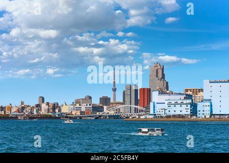 tokio, japan - märz 15 2020: Wasserbusse fahren vor der Arch-Brücke von Tsukiji Ohashi auf dem Sumida-Fluss mit den Wolkenkratzern von Tsukiji an Stockfoto