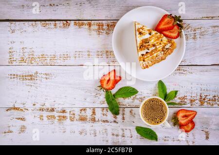 Stück Karamellkuchen mit Tasse Kaffee auf weißem rustikalem Holzhintergrund. Stockfoto