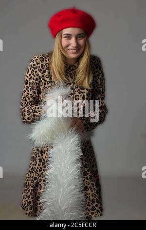 Studio-Porträt eines Mädchens in einer dunklen Jacke und gestreifte Hose auf weißem Hintergrund-Isolat. Durch die Finger zu beobachten Stockfoto