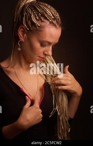 Mode Studio Shoot Frau . mit einer kreativen bunten Frisur in Form eines Zischucks geflochten von Dreadlocks Afro-Pigtails in der Technik der zizi. Stockfoto